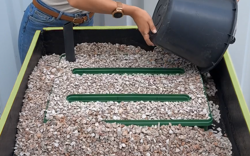 Beim Einbau des Regadios wird mit einem Eimer rund um das Regadio der Splitt aufgefüllt